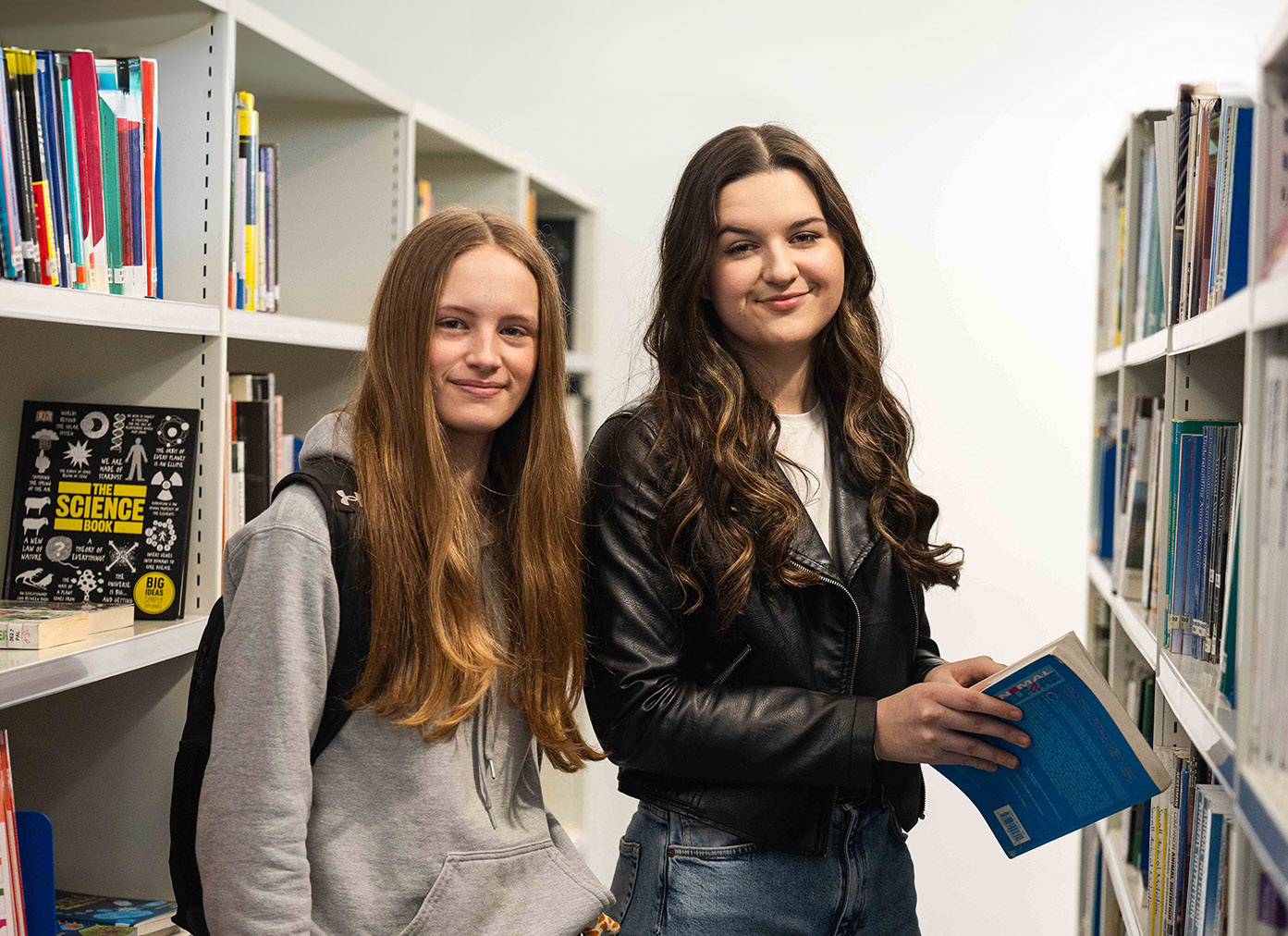Two students holding book in Usk library