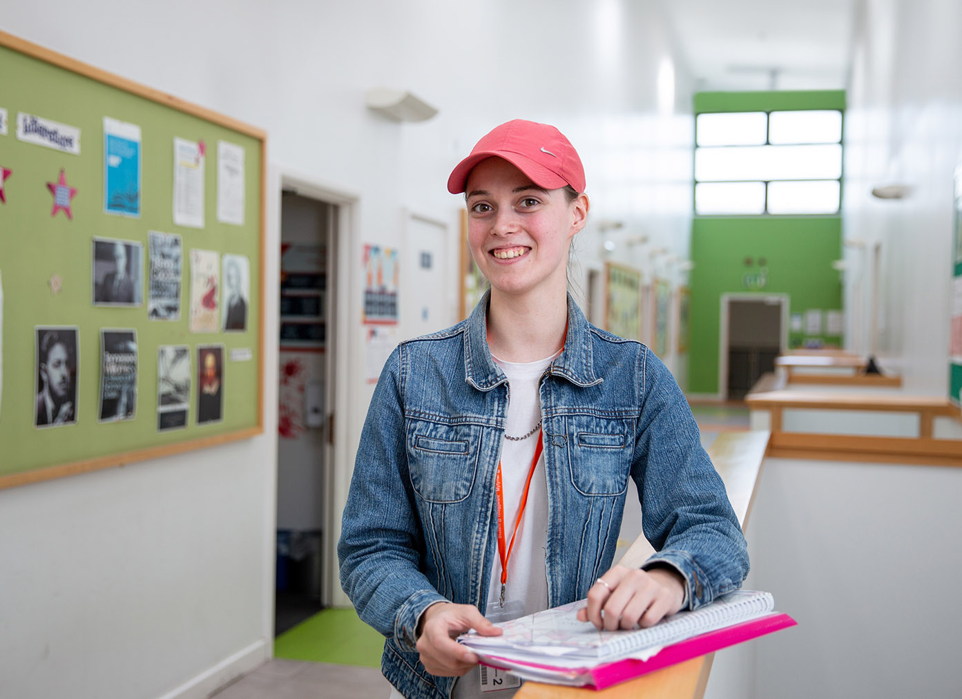 Student in cap stood smiling in campus corridor
