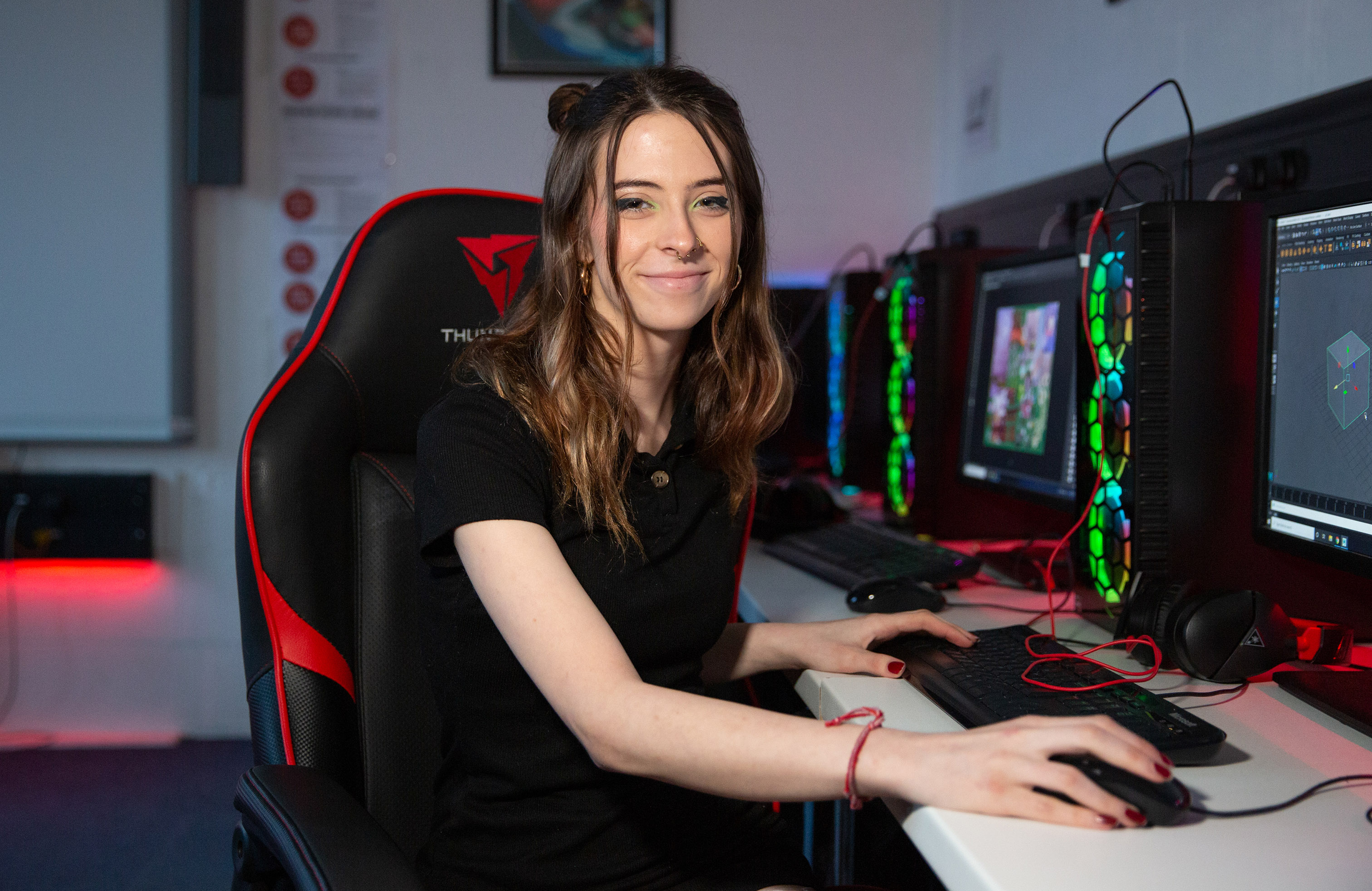 Games design student at computer with neon lights