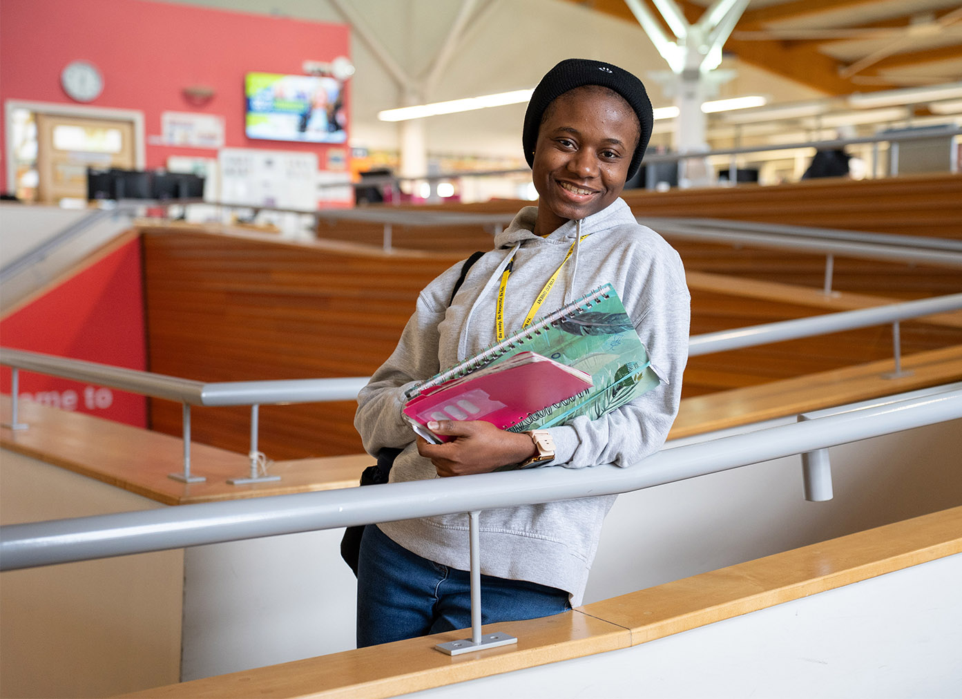 Smiling student stood on stairway holding books