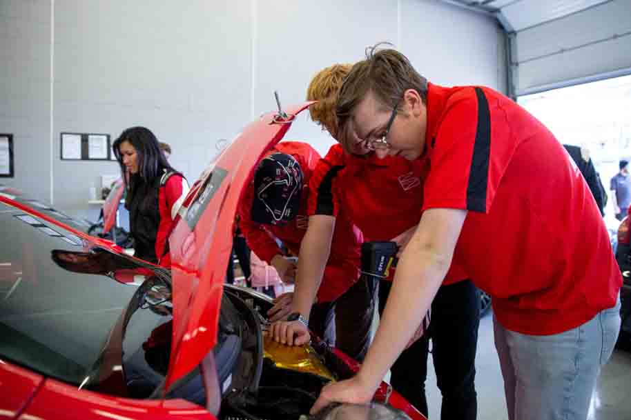 Students working together to fix car engine