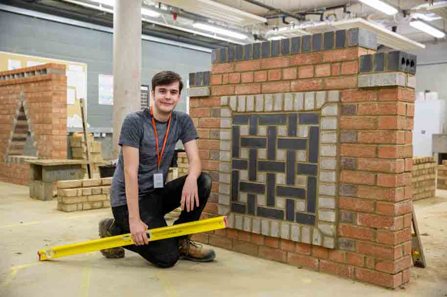 Young Adult student against brick wall