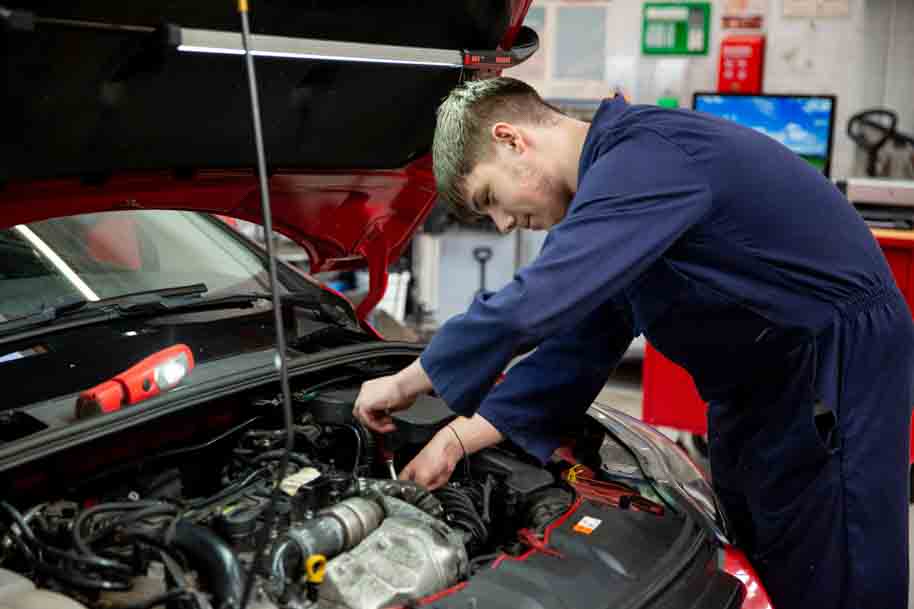 Student investigating car with open hood