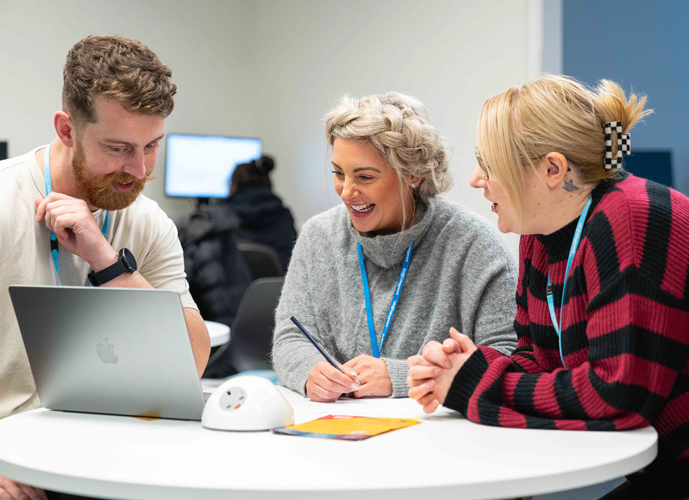 Three students sat around a laptop