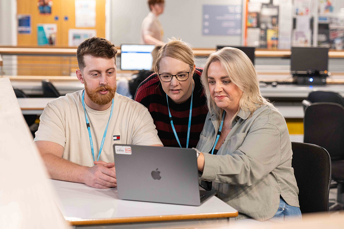 Three students looking at a laptop