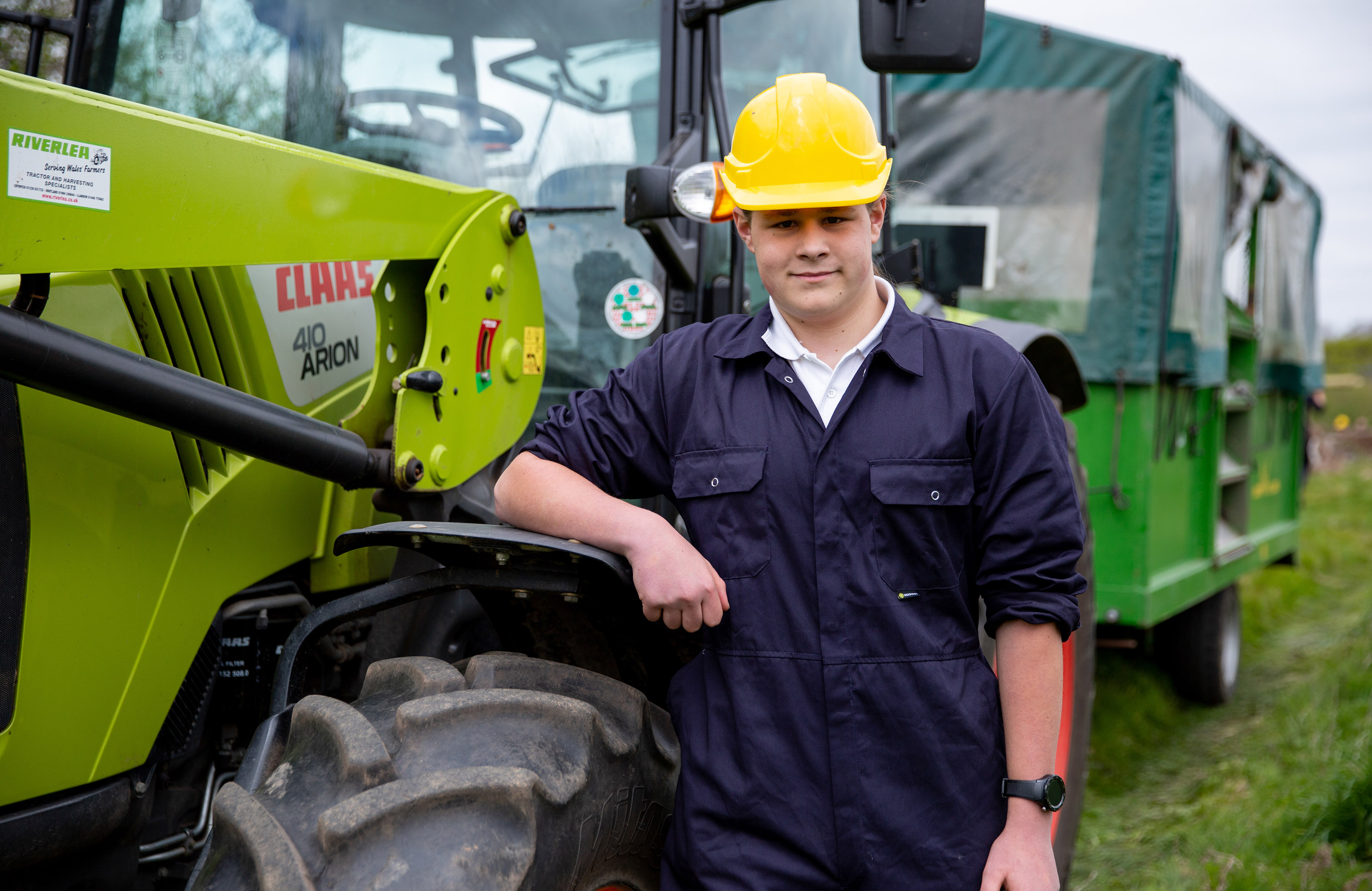 Land-based student stood next to a tractor