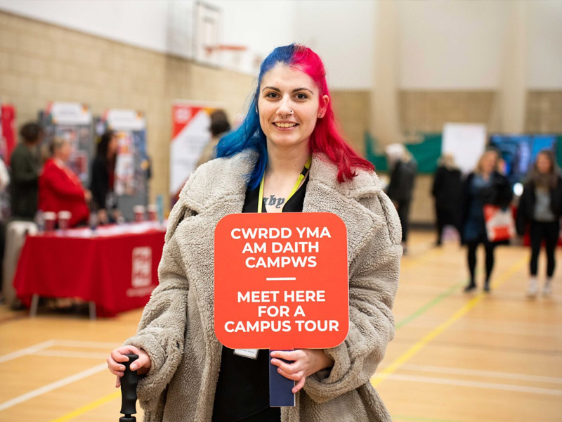 Student ambassador with a campus tour sign